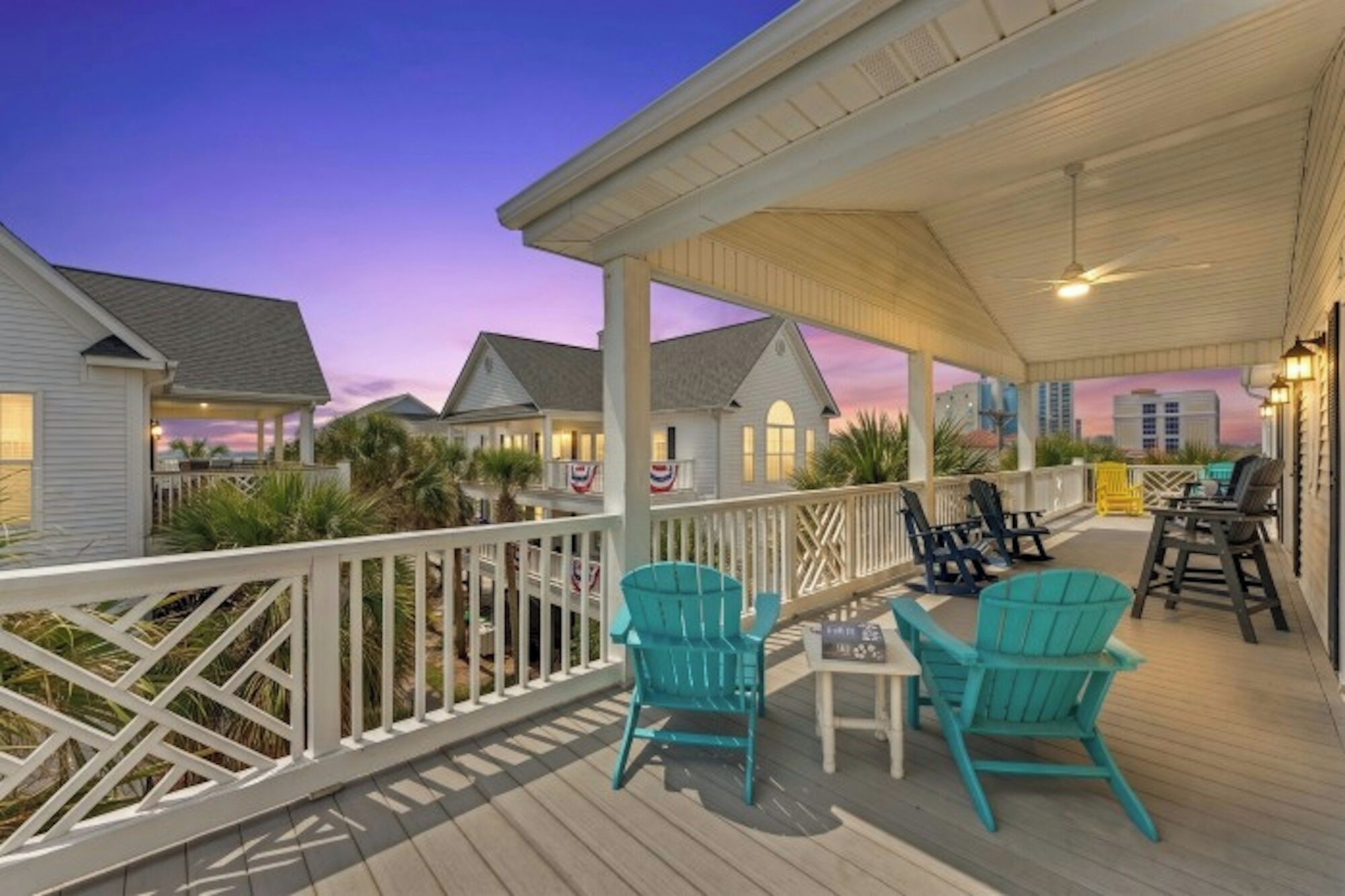 A covered outdoor deck with seating and a view of neighboring houses.