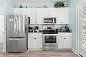 A modern kitchen with stainless steel appliances, white cabinetry, and a granite countertop. - Sunshine Daydream - Close to Beach/Shared Pool (North Myrtle Beach)
