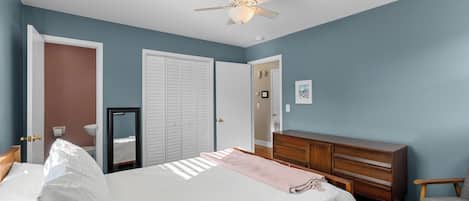 A bedroom with a bed, dresser, mirror, and a ceiling fan.