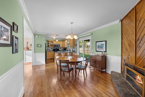 A spacious dining area with a wooden table and chairs, a kitchen in the background, and a fireplace. - Modern home - 15 mins to DT Nashville & BNA (Antioch)