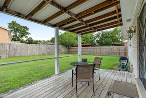 A covered patio with a table and chairs, a wooden deck, and a view of a backyard with a wooden fence. - Modern home - 15 mins to DT Nashville & BNA (Antioch)