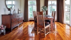 Uma sala de jantar com mesa e cadeiras de madeira, um aparador com gavetas e um espelho na parede.