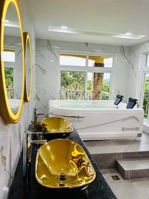 A modern bathroom with a large bathtub, two gold-colored sinks, and a large mirror. - Monk Punta Fuego Beach House (Nasugbu)