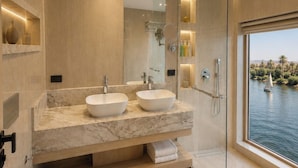 Un baño moderno con dos lavabos, inodoro y cabina de ducha de vidrio.