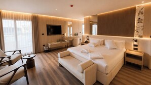 Una habitación de hotel moderna con una cama grande, un escritorio, un televisor y una zona de estar.