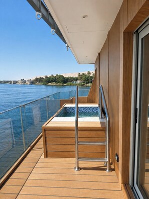 A deck with a glass balustrade overlooking a body of water, a wooden deck, and a glass door leading to an interior space. - Rafaheya Nile Cruise Monday 4 nts Luxor - All Inclusive (Luxor)
