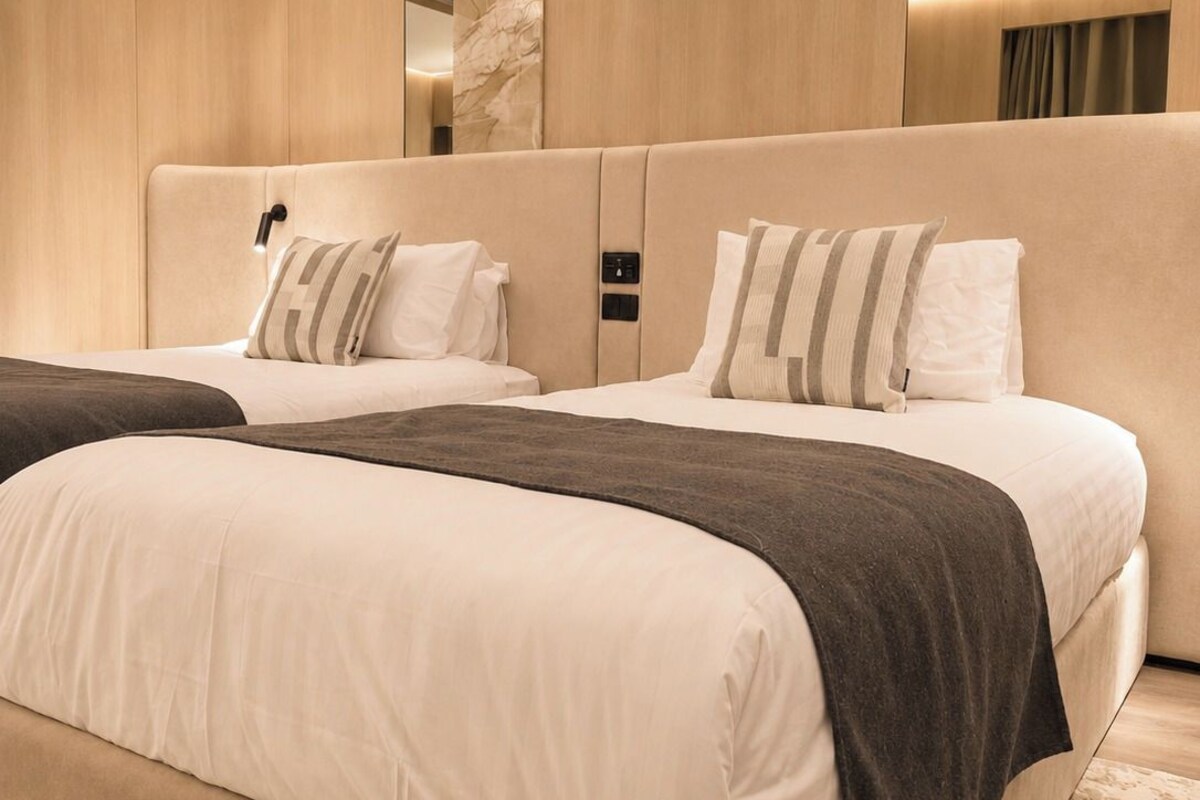 A modern bedroom with a large bed, a bedside table, and a mirror.