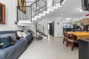 A modern interior with a staircase, a dining area, and a living room with a sofa.