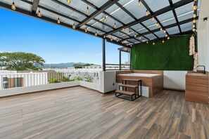 Een balkon met een houten vloer, een groene wand en een bad.