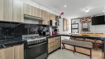 A modern kitchen with a gas stove, oven, and wooden cabinets.