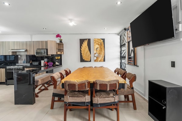 A modern kitchen with built-in appliances and a dining area with a large wooden table and cushioned chairs.