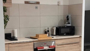 Cozinha moderna com forno Bosch embutido, micro-ondas e máquina de café na bancada.