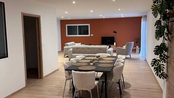 Un vaste espace de vie comprenant une grande table à manger, des canapés et un téléviseur.