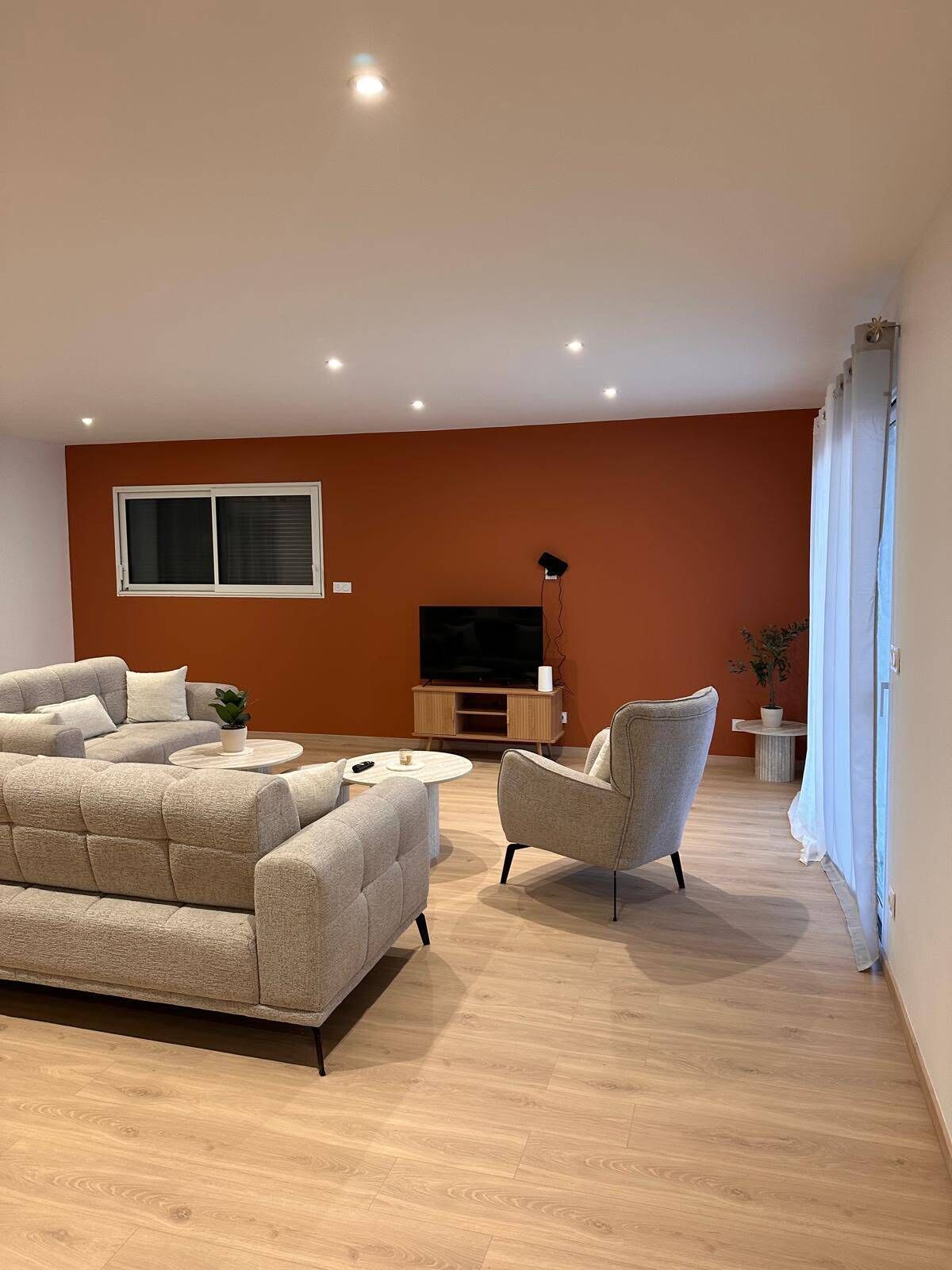 A modern living room with a sofa, armchair, and a TV stand.