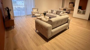 Uma sala de estar ampla com um sofá grande, uma mesa de centro e um espaço de jantar com cadeiras.