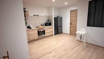 Une cuisine moderne équipée d’un four à micro-ondes, d’un réfrigérateur et de meubles de rangement en bois.
