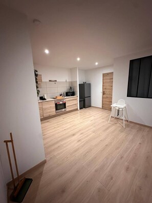 Une cuisine moderne équipée d’un four à micro-ondes, d’un réfrigérateur et de meubles de rangement en bois.