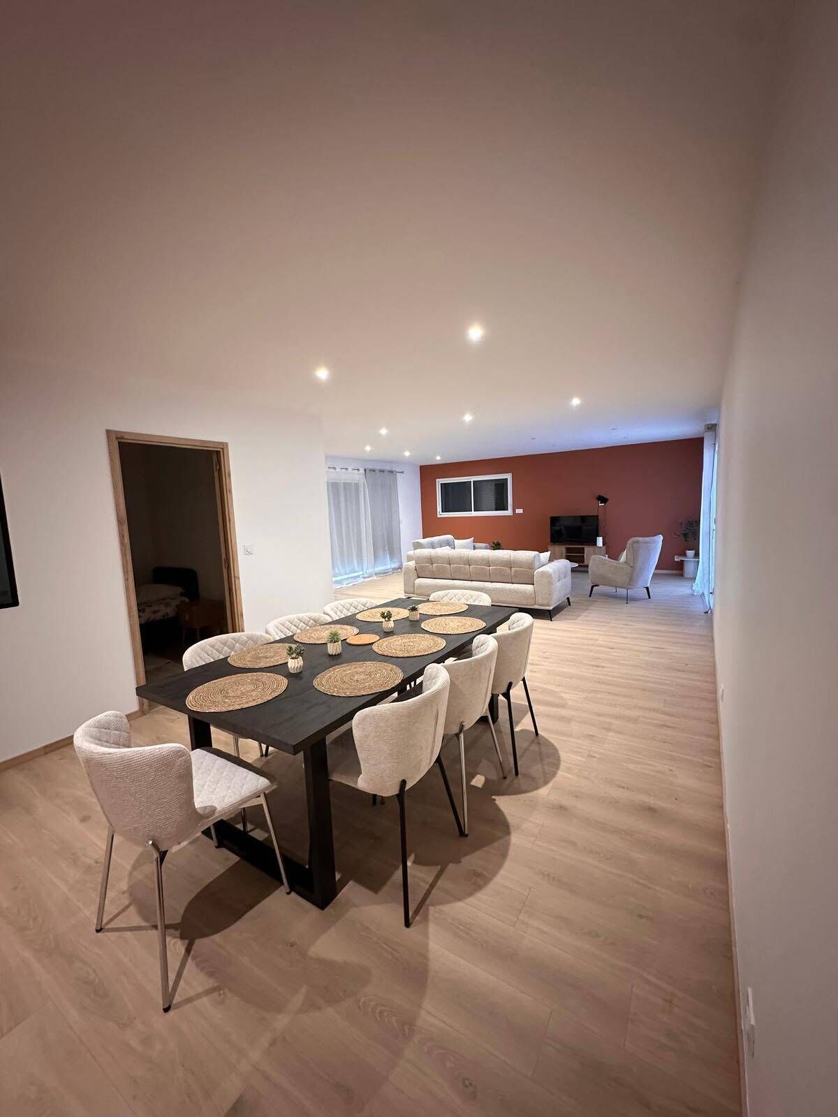 A modern dining area with a dark table, white chairs, and woven placemats.