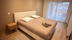 Quarto com cama grande, mesa de cabeceira e janela com cortinas.