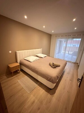 A bedroom with a large bed, a bedside table, and a window with curtains. - The Volcanoes Refuge (Saint-Pierre-le-Chastel)