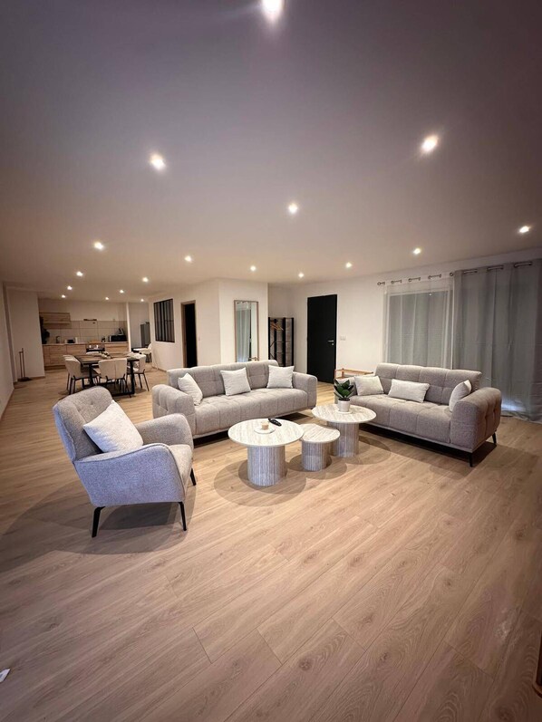 A spacious living area with two sofas, a coffee table, and a dining table. - The Volcanoes Refuge (Saint-Pierre-le-Chastel)