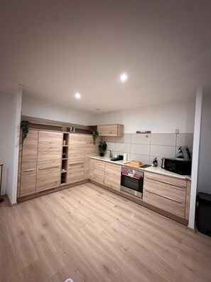 Une cuisine moderne avec des meubles en bois, un four encastré et un four à micro-ondes.