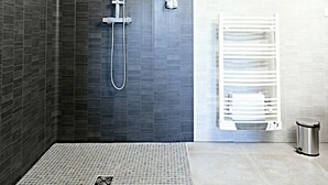 Uma área de chuveiro moderna com um chuveiro de efeito chuva, um chuveiro manual e um painel de controle.