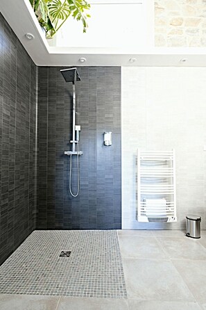 A modern shower area with a rain showerhead, a handheld showerhead, and a control panel. - Vrbo Property (Nîmes)