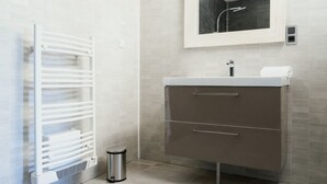 Casa de banho moderna com toucador branco, espelho e porta-toalhas.