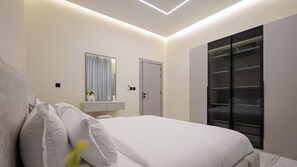 Ein modernes Schlafzimmer mit Bett, Nachttisch, Spiegel, Kleiderschrank und integrierter Beleuchtung.