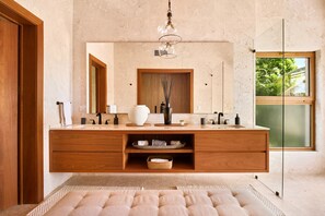 Une salle de bain moderne avec un meuble-lavabo en bois, un grand miroir et une fenêtre donnant sur un paysage verdoyant.