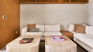 A modern living room with a sofa, two coffee tables, and a wooden shelf unit.