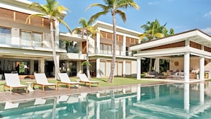 A modern resort with a swimming pool, lounge chairs, and palm trees.