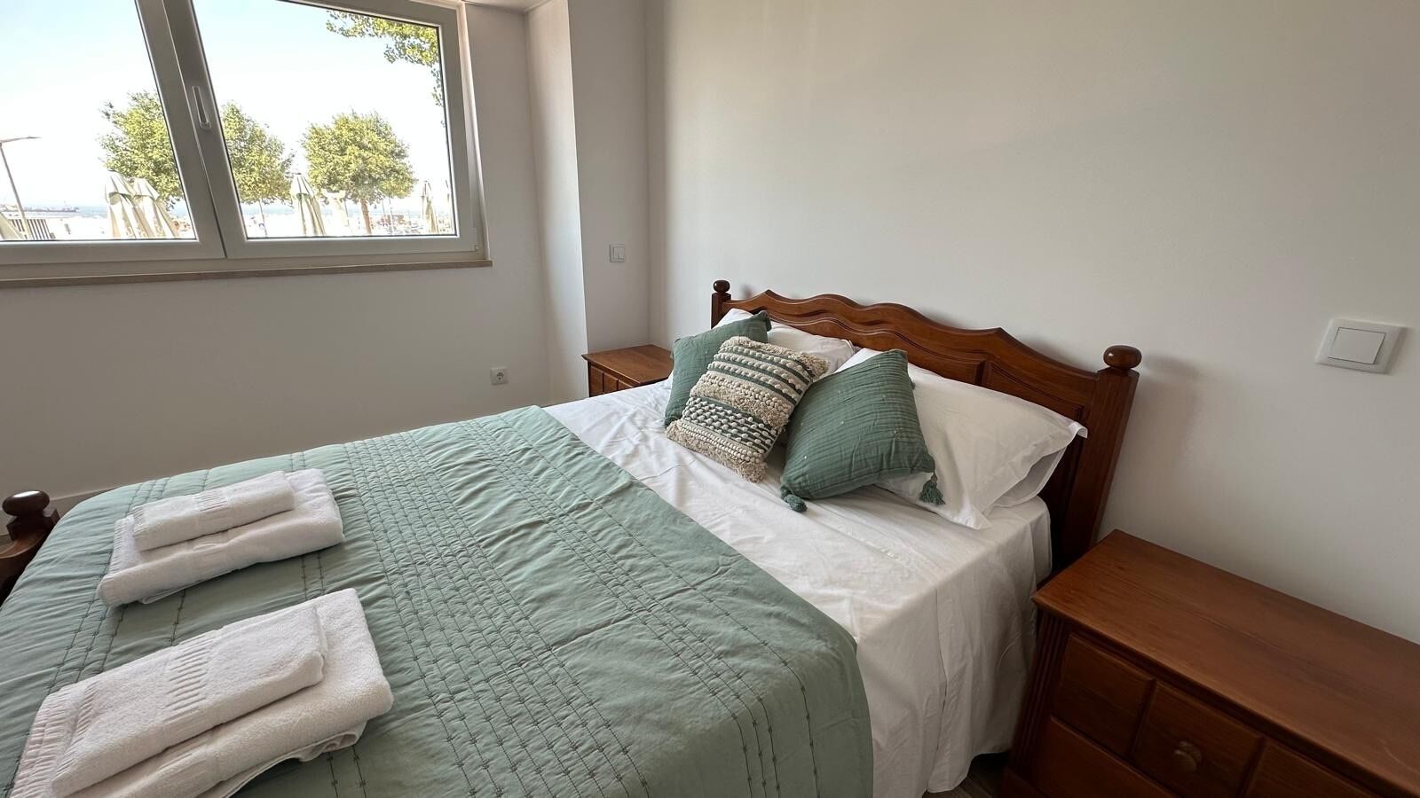 A bed with a quilt, pillows, and folded towels.