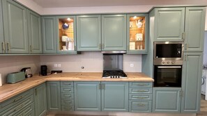 A kitchen with teal cabinets, a gas stove, a microwave, and an oven. - A spacious and comfortable house, just 300 meters from the beach; pets welcome. (Buarcos)