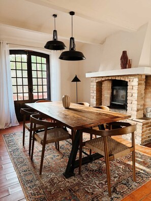 A dining area with a wooden table, chairs, a fireplace, and hanging pendant lights. - Historic stone house with a pool between the Cévennes and the Ardèche (Saint-Victor-de-Malcap)