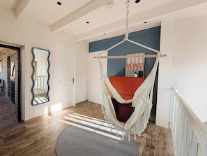 A room with a hanging hammock chair, a wooden floor, a patterned rug, and a door with a mirror. - Historic stone house with a pool between the Cévennes and the Ardèche (Saint-Victor-de-Malcap)