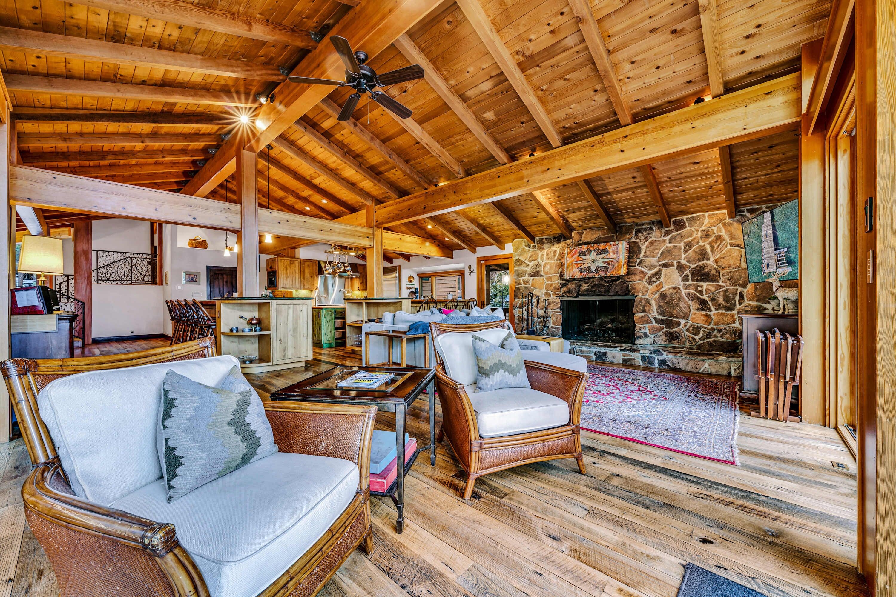 A spacious living area with wooden beams, a stone fireplace, and comfortable seating.