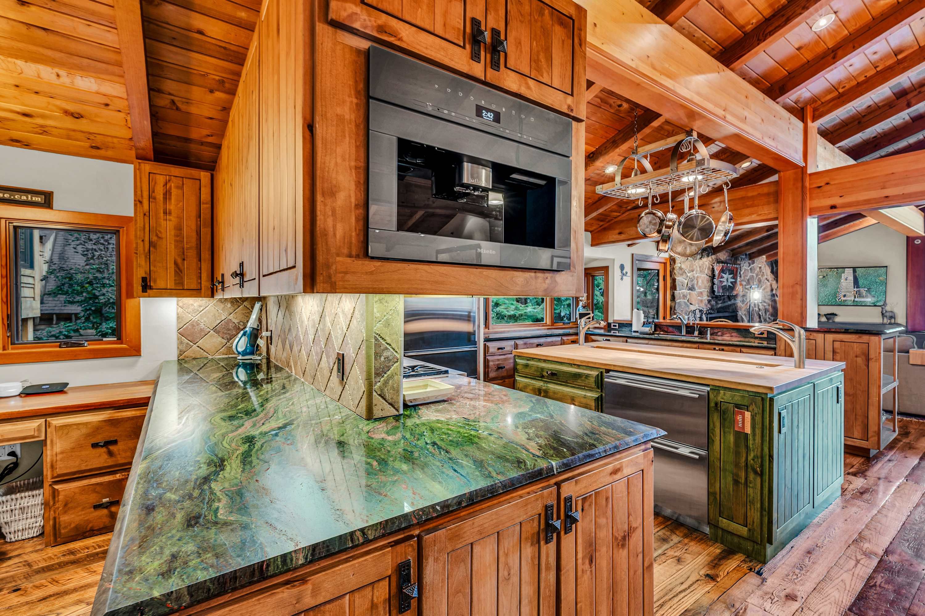 A kitchen with wooden cabinets, a stainless steel range hood, and a large island with a marble countertop.