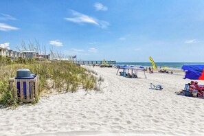 En strand med en moler, strandparasoller og en livredderstand.