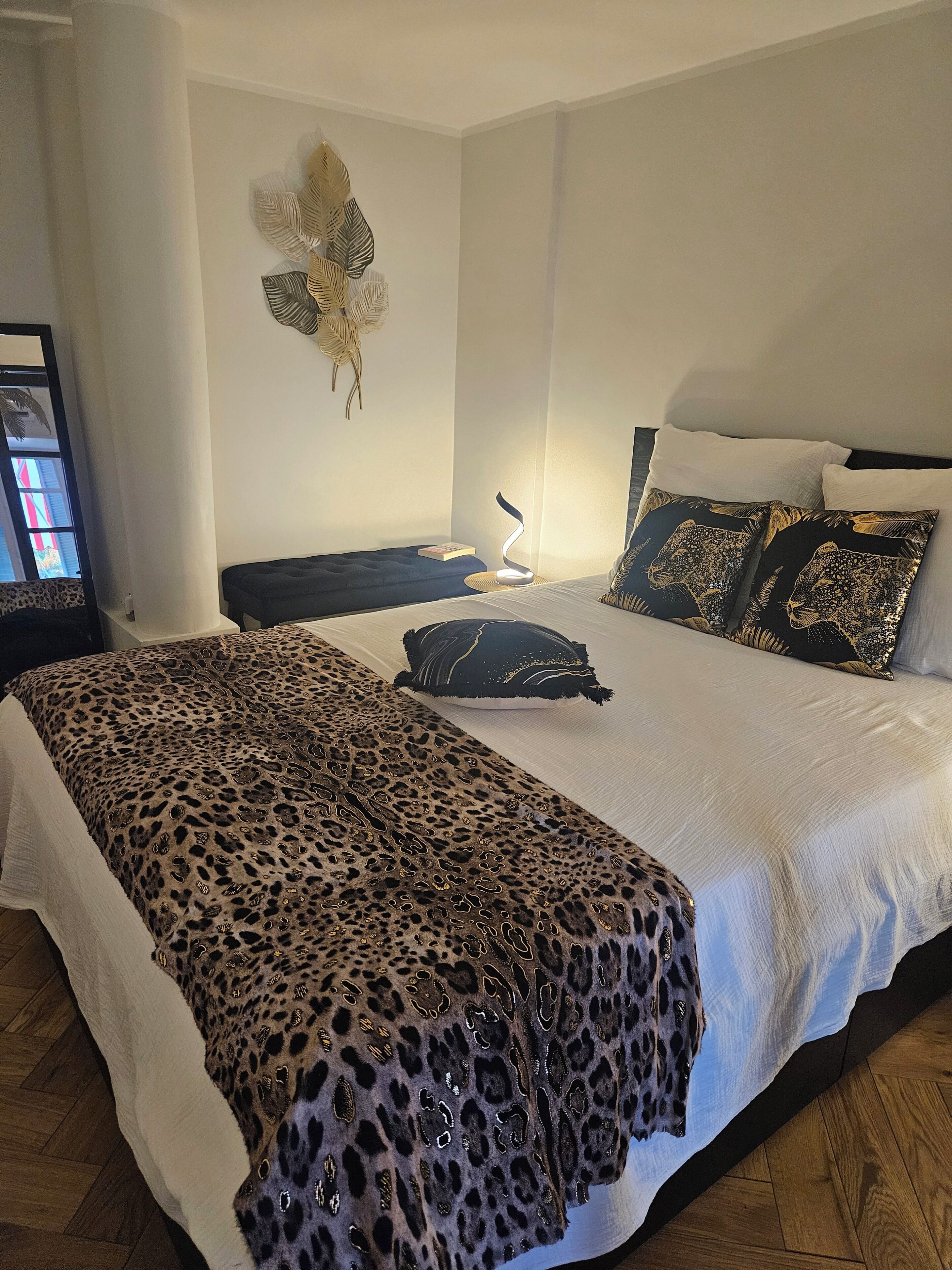 Une chambre à coucher avec un lit, des oreillers, une table de chevet, un élément de décoration murale et une lampe.