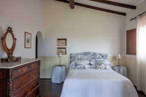 Ein Schlafzimmer mit einem großen Bett, einer hölzernen Kommode, zwei gerahmten Bildern und einem Spiegel.