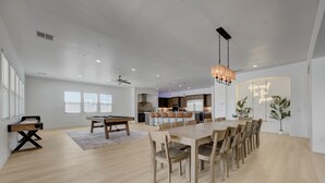 Amplia sala de estar con una mesa de comedor, mesa de billar y una cocina al fondo.