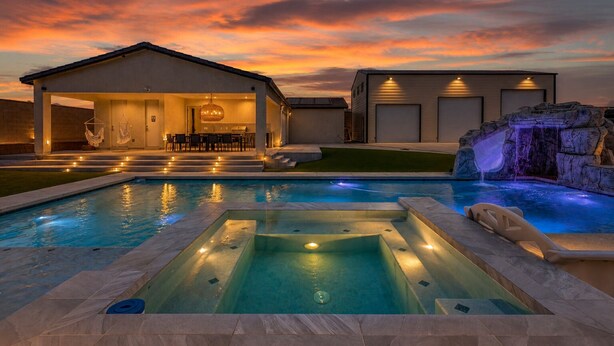 Una piscina con jacuzzi, un patio cubierto y una cascada.