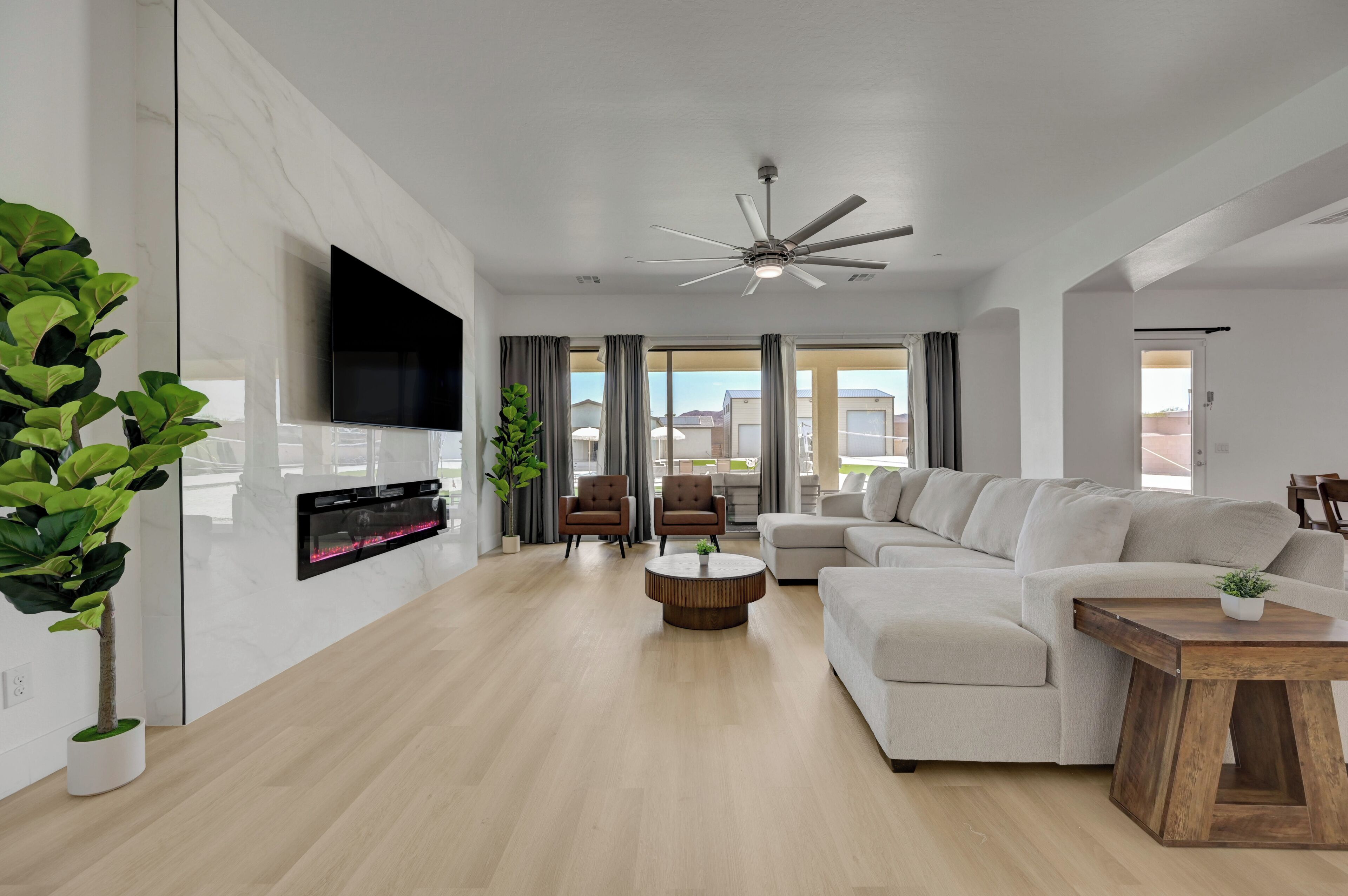 A modern living room with a flat-screen TV, a ceiling fan, a sectional sofa, and a coffee table.