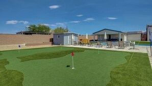 Un campo de mini golf con un putting green, hoyos de arena y un pequeño edificio.