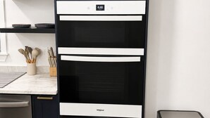 Una cocina con un armario negro, un microondas y un cubo de basura de acero inoxidable.