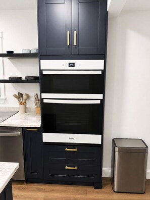 Een keuken met een zwart kastje, een magnetron en een roestvrijstalen prullenbak.