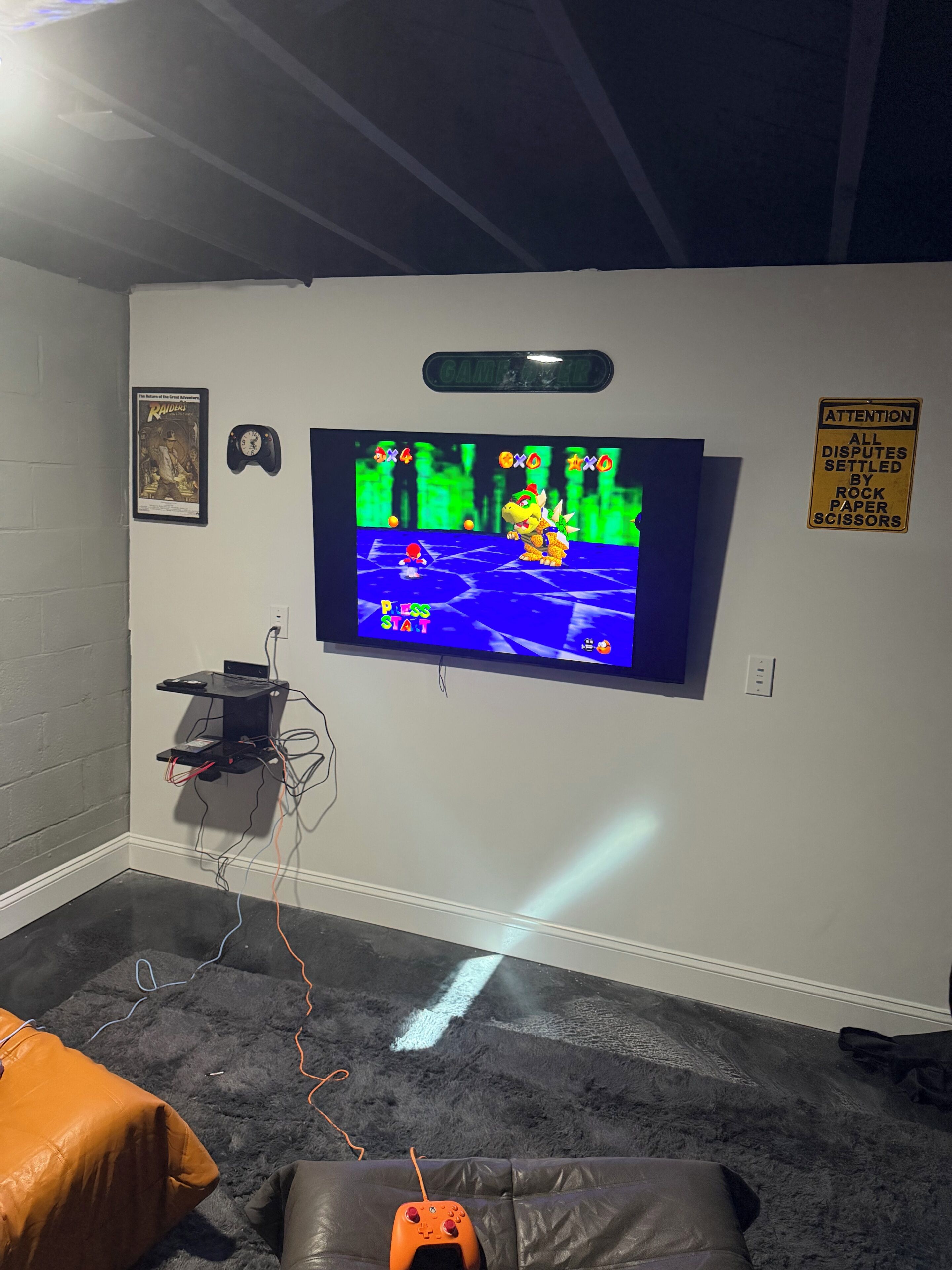 A gaming room with a television displaying a video game, a clock, and a sign on the wall.