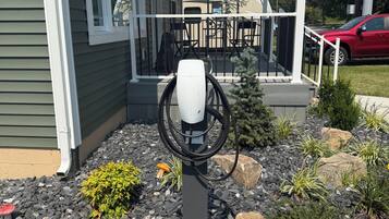 A residential property with a covered porch, a Tesla charging station, and a landscaped garden with rocks and plants.
